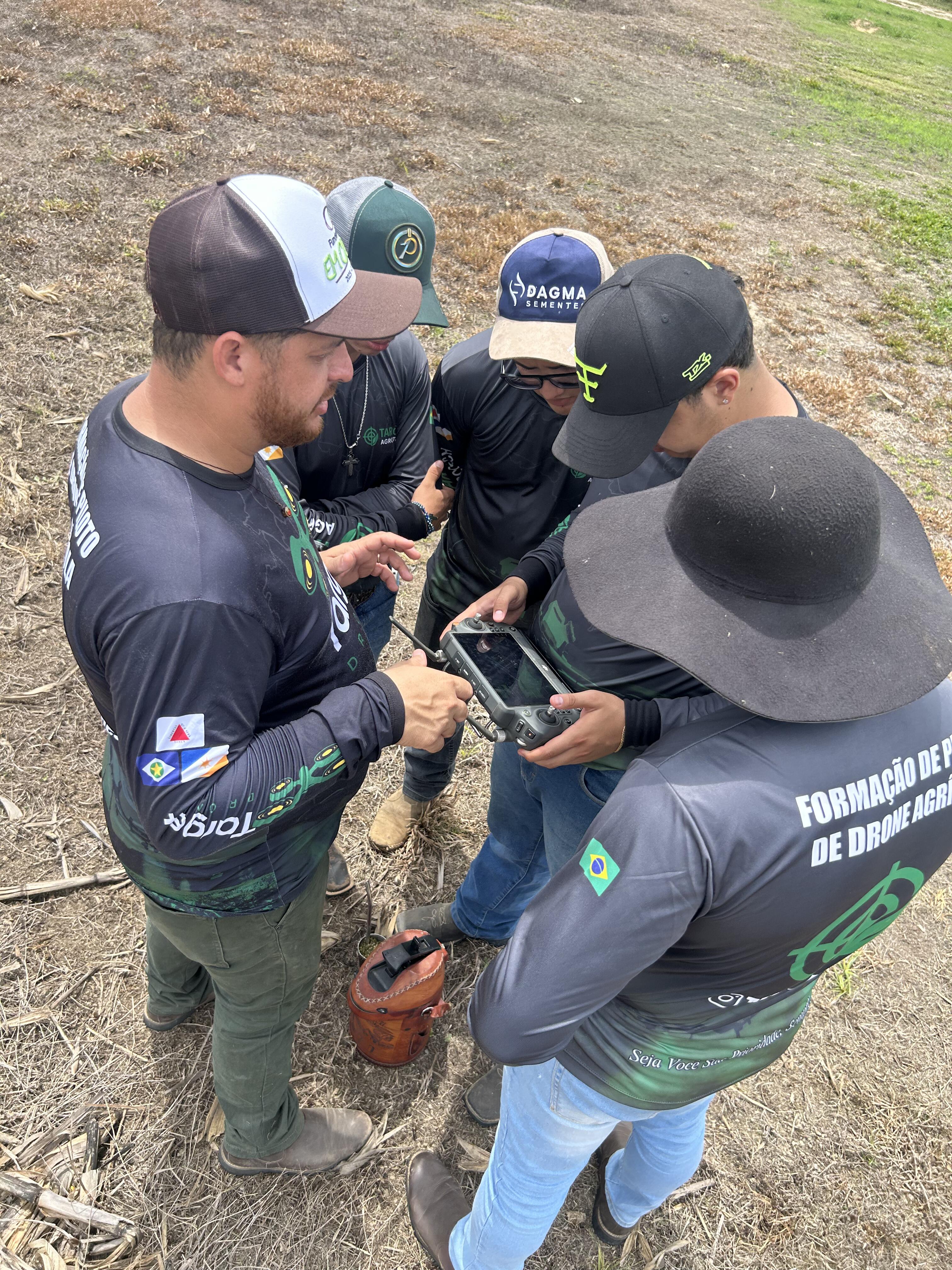 Grupo de alunos reunidos em volta do controle do drone agrícola analisando os dados de voo