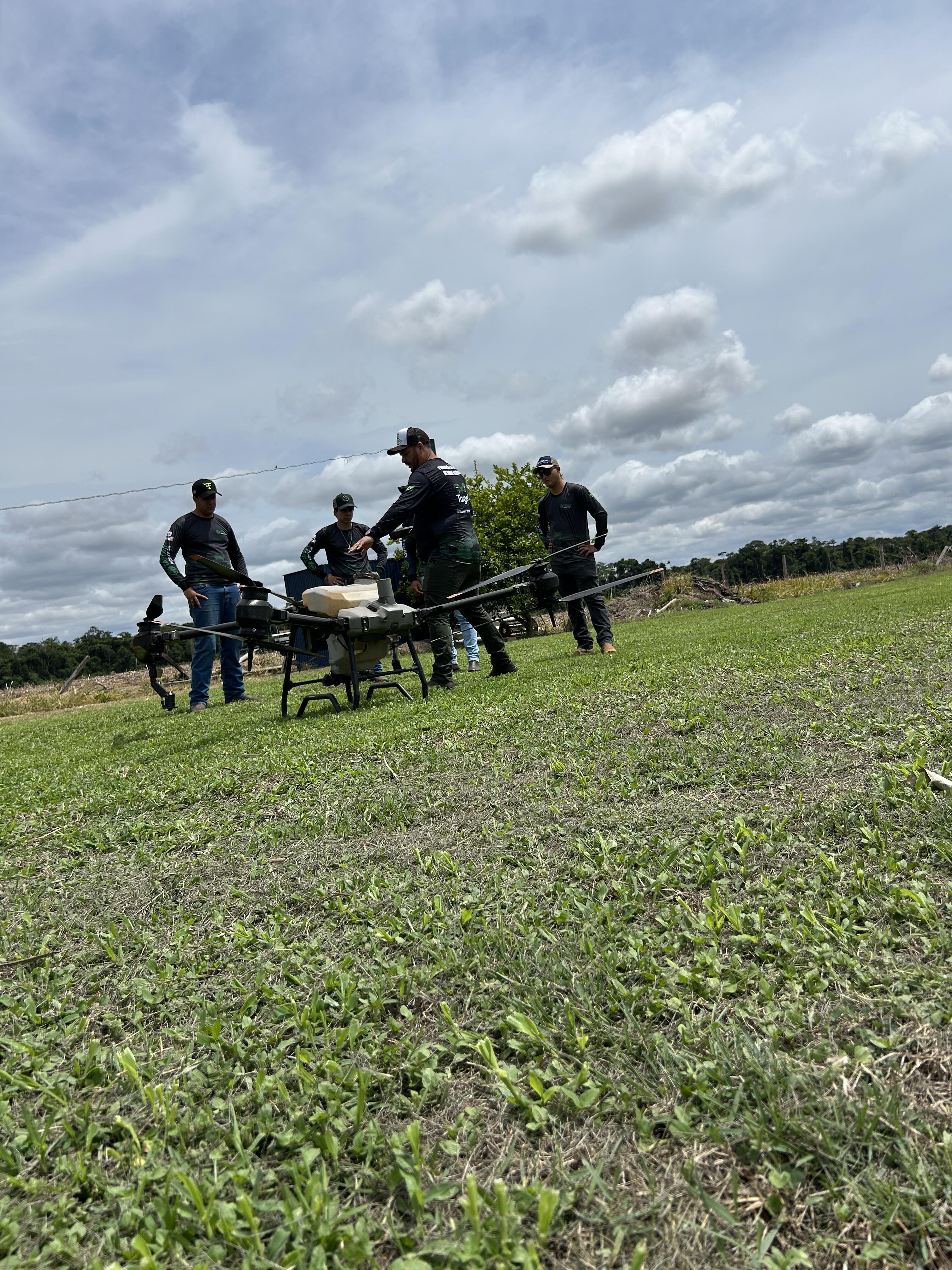 Turma de Piloto de Drone Agrícola ajustando o drone antes da decolagem em área de campo aberto